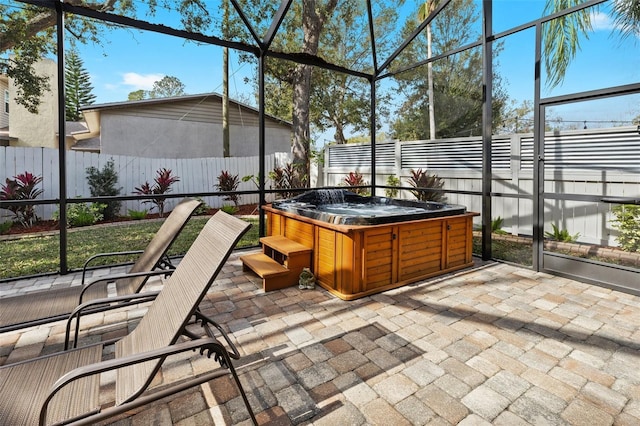 view of patio with glass enclosure, a hot tub, and a fenced backyard