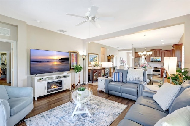 living area featuring a glass covered fireplace, wood finished floors, and visible vents