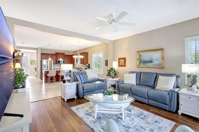 living room with plenty of natural light, wood finished floors, and ceiling fan with notable chandelier