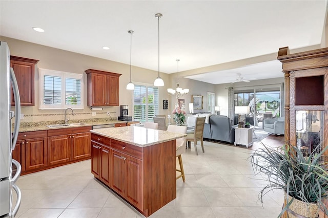 kitchen with freestanding refrigerator, a sink, a kitchen breakfast bar, and light stone countertops