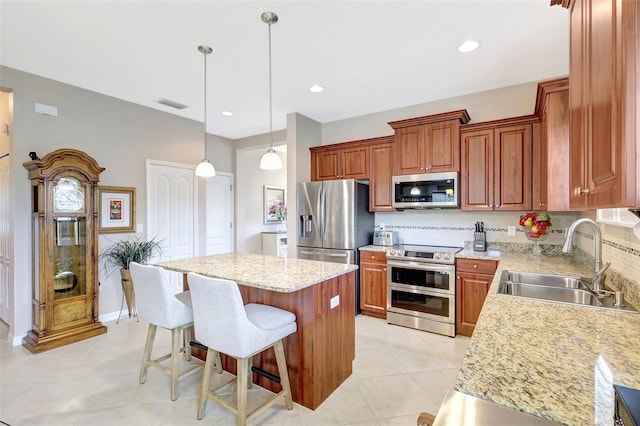 kitchen with visible vents, backsplash, appliances with stainless steel finishes, a sink, and a kitchen island