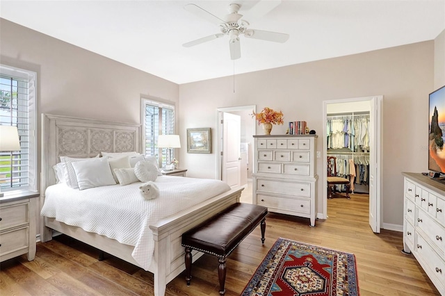 bedroom with light wood-style floors, a closet, multiple windows, and a spacious closet