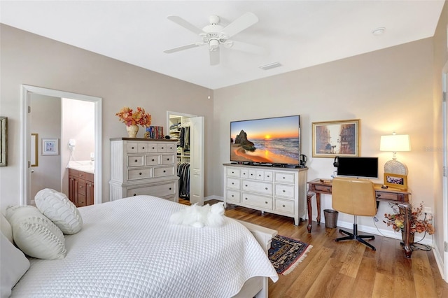 bedroom featuring baseboards, connected bathroom, wood finished floors, a spacious closet, and a closet