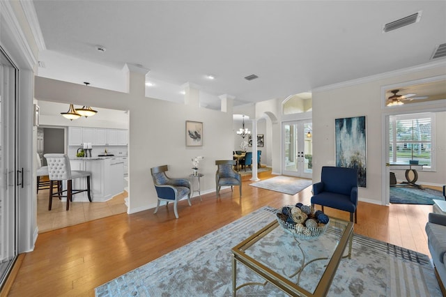 11815 Marblehead Dr, Tampa, FL 33626 - living area featuring french doors, ornamental molding, arched walkways, light wood finished floors, and visible vents