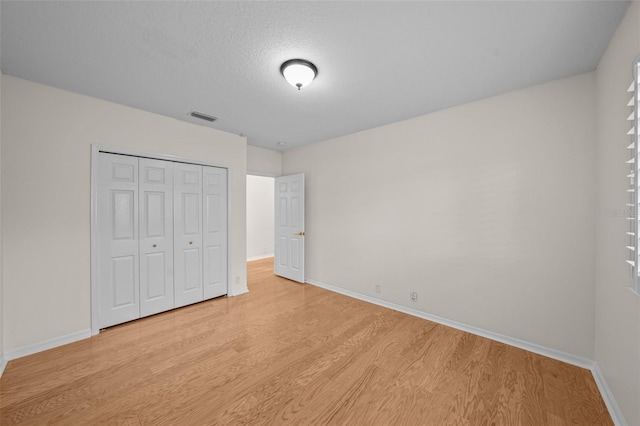 11815 Marblehead Dr, Tampa, FL 33626 - unfurnished bedroom with baseboards, a textured ceiling, light wood-style floors, visible vents, and a closet
