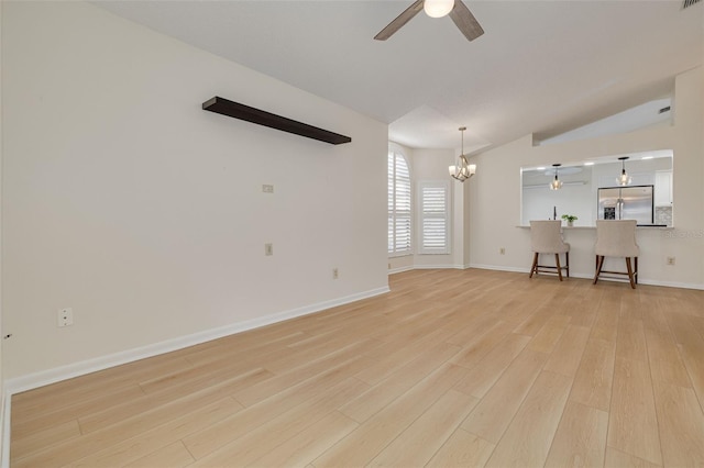 unfurnished living room with light wood finished floors, visible vents, vaulted ceiling, baseboards, and ceiling fan with notable chandelier