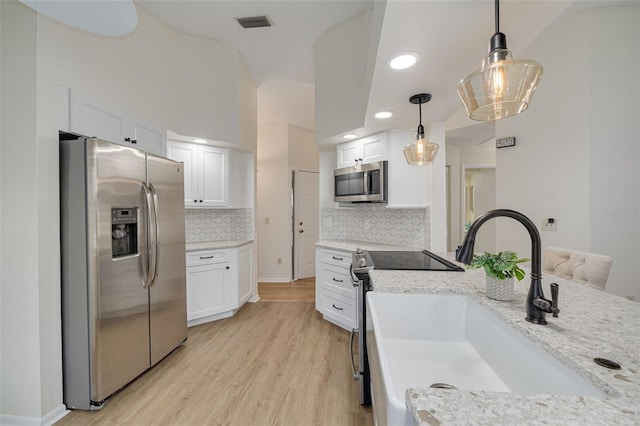 kitchen with stainless steel appliances, a sink, white cabinetry, hanging light fixtures, and light wood-type flooring