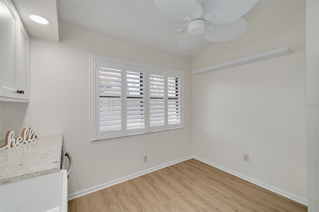 unfurnished dining area with ceiling fan, a textured ceiling, light wood-type flooring, and baseboards