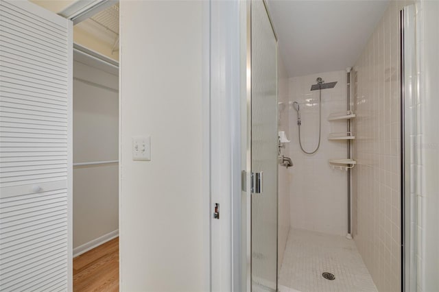 full bathroom with a stall shower, baseboards, and wood finished floors