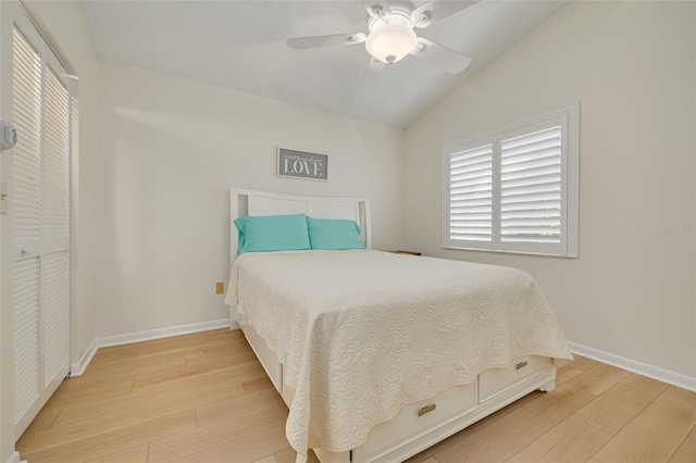 bedroom featuring lofted ceiling, light wood-style flooring, baseboards, and ceiling fan