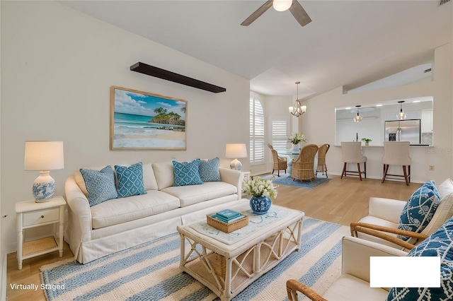 living area with lofted ceiling, visible vents, light wood-style flooring, and ceiling fan with notable chandelier