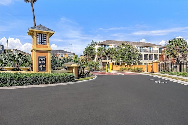 view of street featuring curbs, sidewalks, a gated entry, and street lights