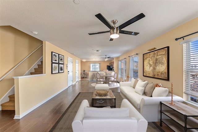 living area with baseboards, ceiling fan, wood finished floors, stairs, and a textured ceiling