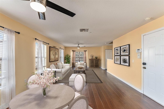 living area with dark wood finished floors, visible vents, ceiling fan, a textured ceiling, and baseboards