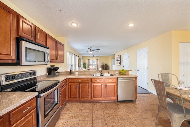 kitchen with light tile patterned flooring, a peninsula, a sink, light countertops, and appliances with stainless steel finishes