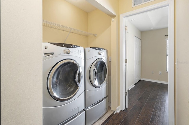 washroom with washing machine and dryer, laundry area, visible vents, baseboards, and dark wood finished floors