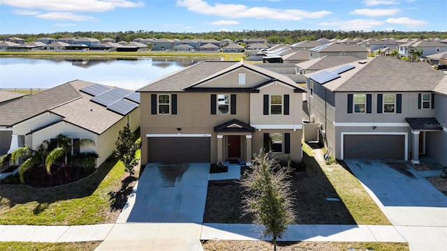 view of front of home with a water view, a residential view, and roof mounted solar panels