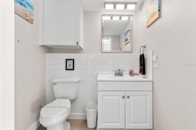 half bathroom with tile walls, toilet, vanity, and tile patterned floors