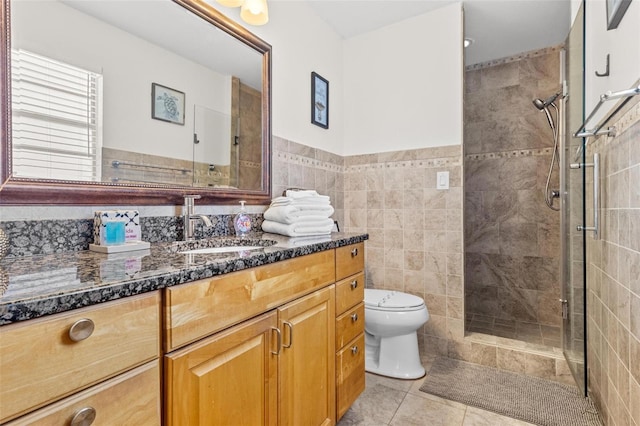 bathroom featuring toilet, vanity, tile patterned floors, and tiled shower