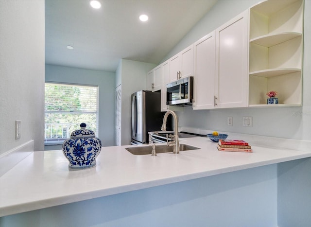 kitchen featuring white cabinets, a peninsula, stainless steel appliances, light countertops, and open shelves