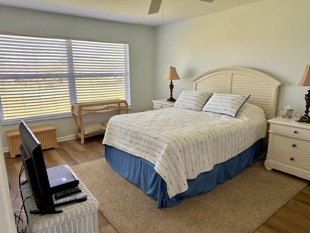 bedroom with light wood finished floors, a ceiling fan, and baseboards