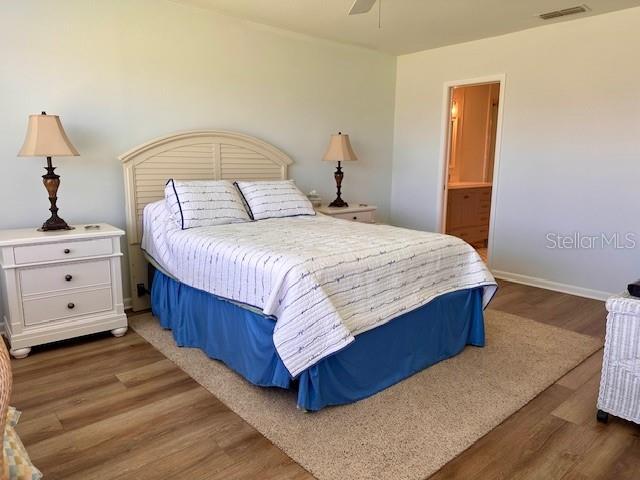 bedroom with dark wood-style floors, visible vents, a ceiling fan, connected bathroom, and baseboards