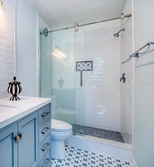 bathroom with toilet, a shower stall, and vanity