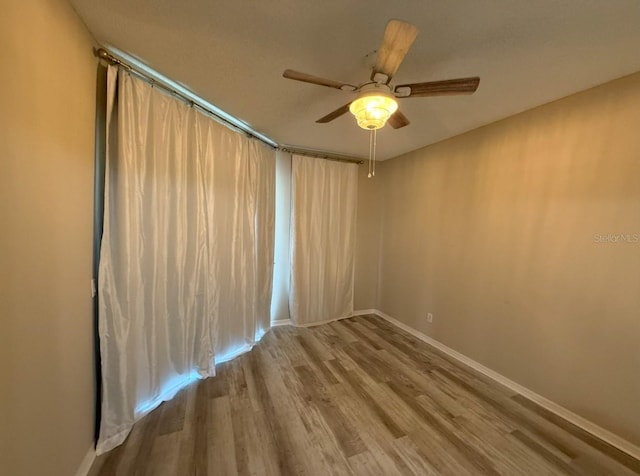 empty room with ceiling fan, baseboards, and wood finished floors