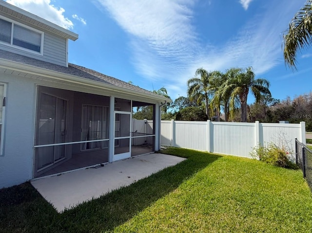 view of yard featuring a patio area, a fenced backyard, and a sunroom