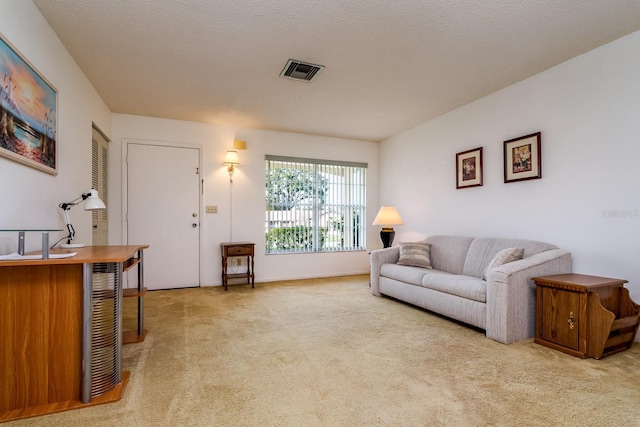 living room featuring a textured ceiling, visible vents, and light colored carpet