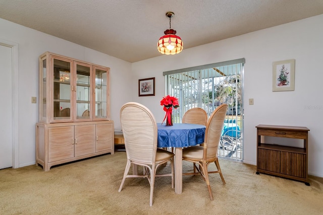 dining room with light colored carpet, a textured ceiling, and baseboards