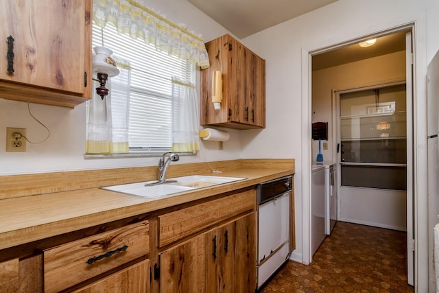 kitchen with brown cabinetry, light countertops, a sink, and white dishwasher