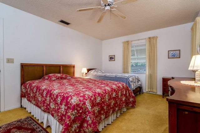 bedroom featuring visible vents, ceiling fan, light carpet, and a textured ceiling