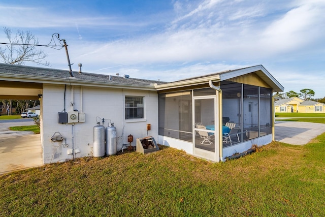 rear view of property featuring a sunroom and a lawn