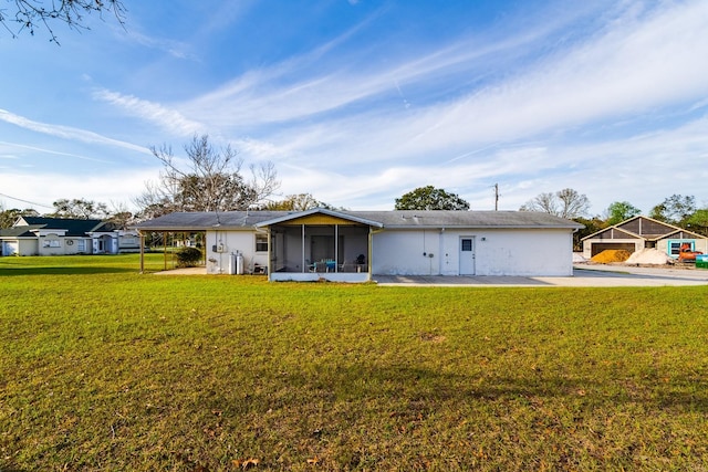 rear view of property featuring a sunroom and a lawn