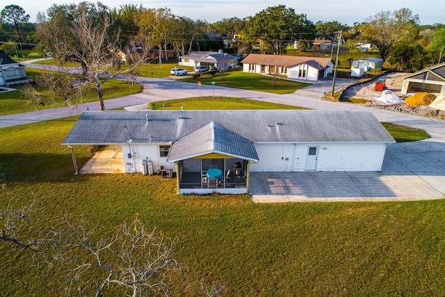 back of property with a shingled roof, a sunroom, and a yard