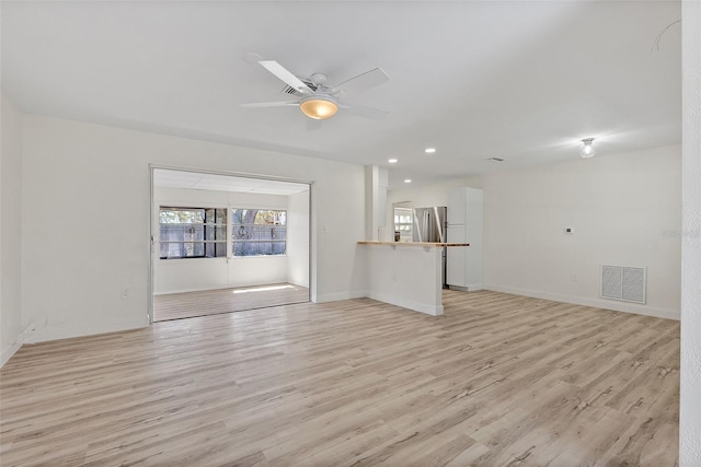 unfurnished living room with ceiling fan, light wood-type flooring, visible vents, and baseboards