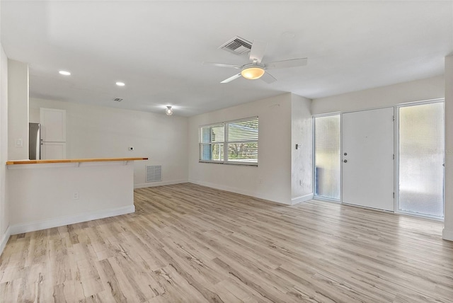 empty room featuring light wood-type flooring, visible vents, and baseboards