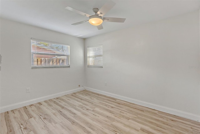 spare room with a ceiling fan, light wood finished floors, and baseboards