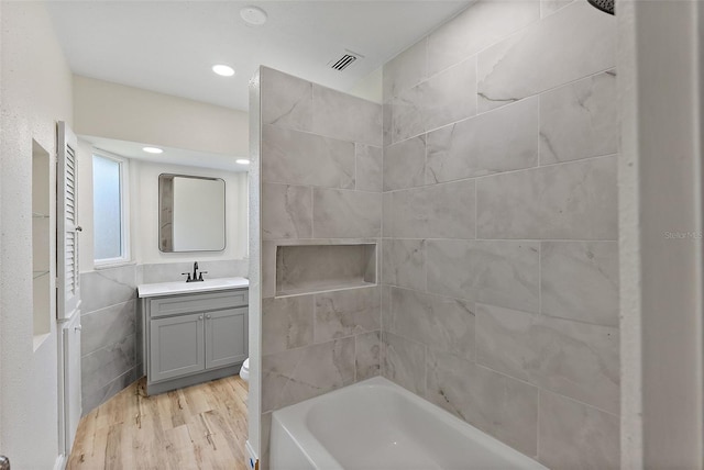 full bath featuring visible vents, shower / bathtub combination, wood finished floors, and vanity