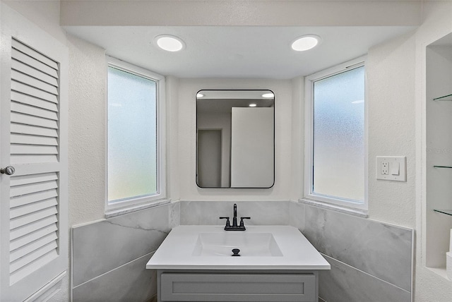 bathroom with vanity and tile walls