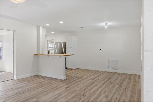 empty room featuring light wood-style floors, baseboards, and visible vents