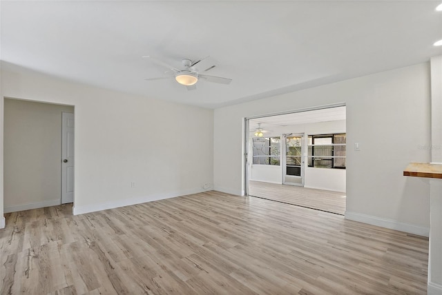 unfurnished room with light wood-type flooring, a ceiling fan, and baseboards