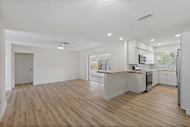 kitchen with visible vents, appliances with stainless steel finishes, a ceiling fan, open floor plan, and a sink