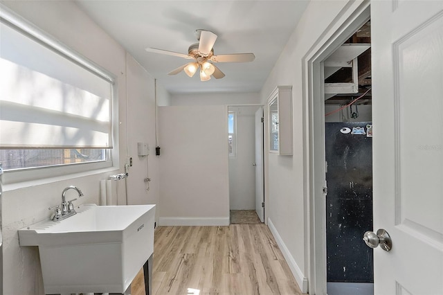 bathroom featuring ceiling fan, baseboards, a sink, and wood finished floors