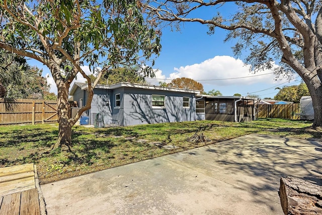 view of front of house with a sunroom, fence, and a front lawn