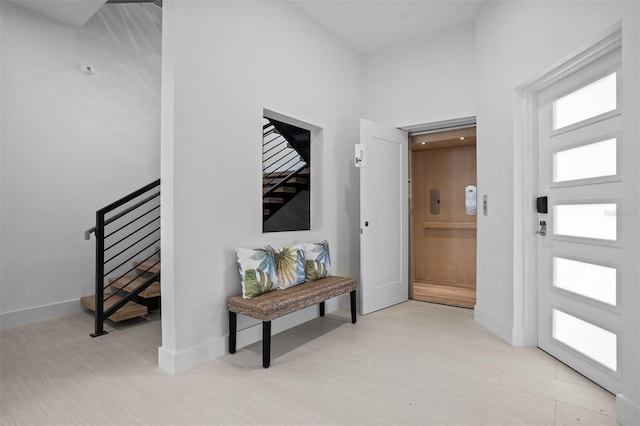 foyer entrance with a healthy amount of sunlight, baseboards, and stairway