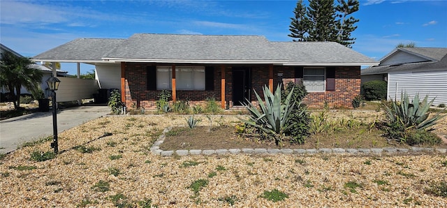 ranch-style home featuring a carport, concrete driveway, brick siding, and a shingled roof