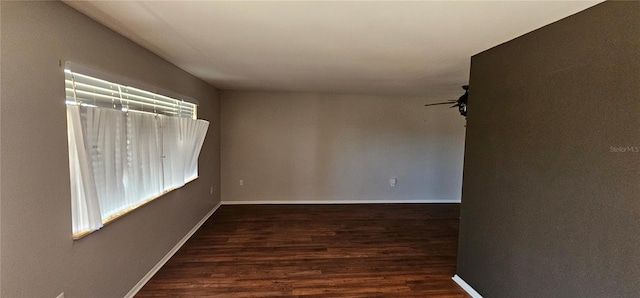 spare room with ceiling fan, baseboards, and dark wood finished floors