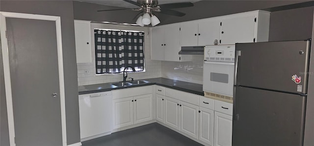 kitchen featuring white appliances, dark countertops, under cabinet range hood, white cabinetry, and a sink